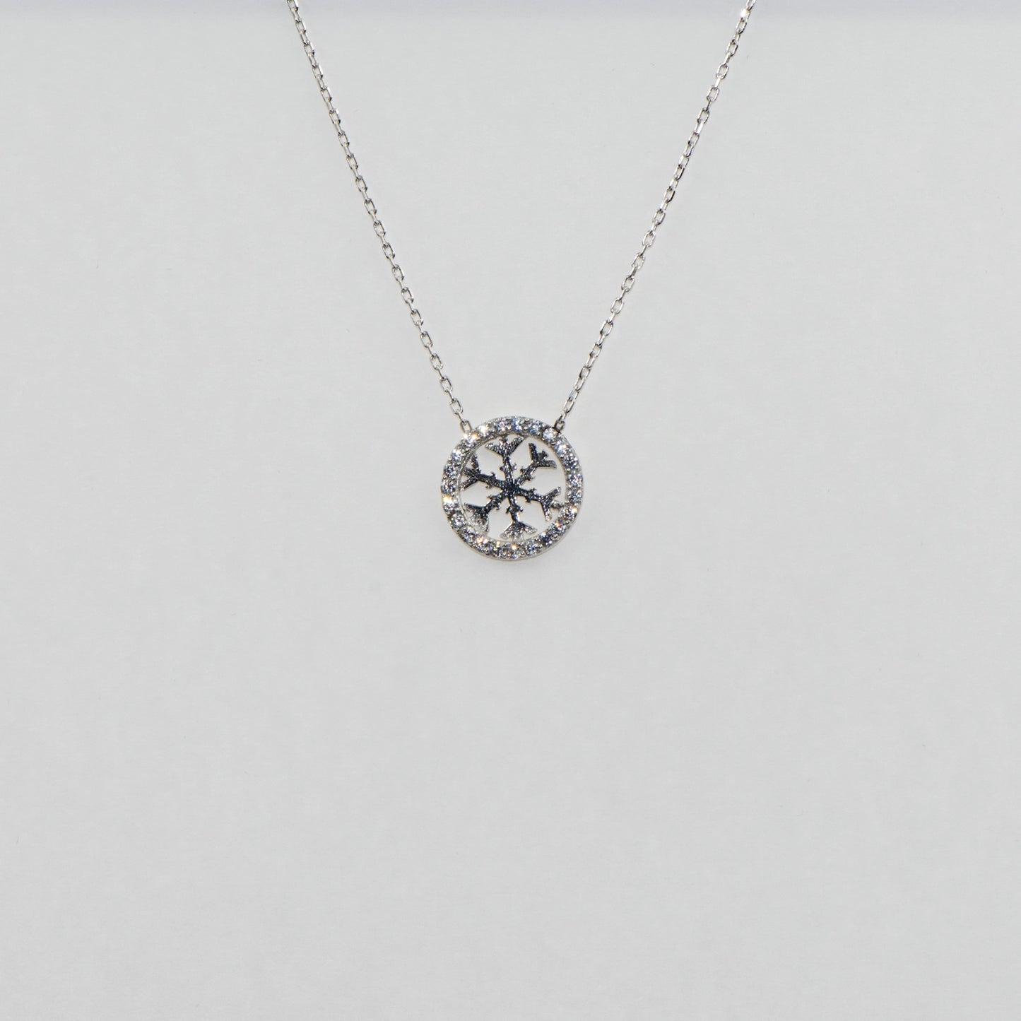 Runde 925 Silber Halskette mit Schneeflocken-Motiv im Kreis. Verziert mit funkelnden weissen Zirkonia-Steinen und rhodinierter Oberfläche.