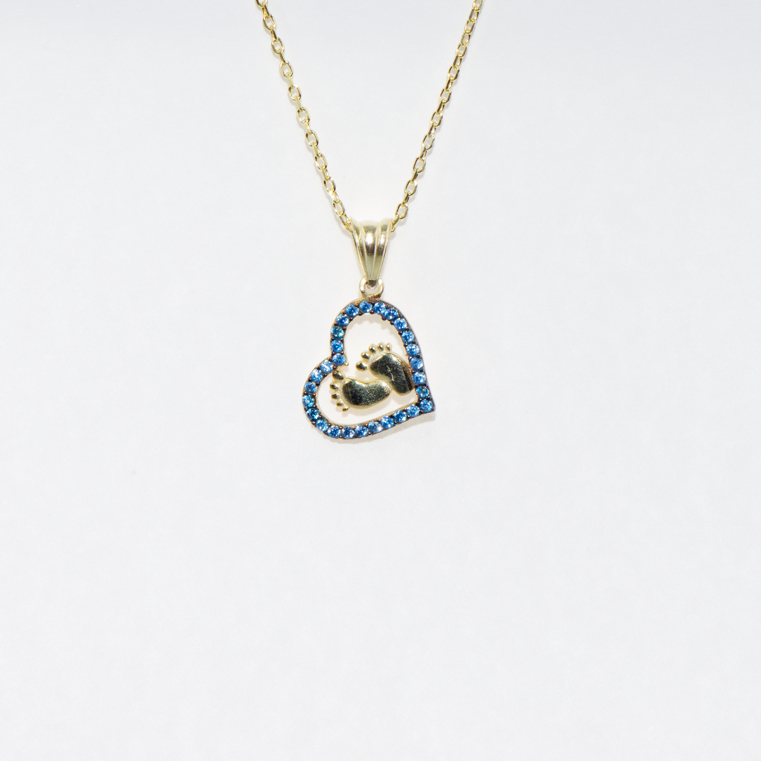 Vergoldete 925 Silber Halskette mit Herz Anhänger und Babyfüssen. Verziert mit funkelnden blauen Zirkonia-Steinen als Symbol für Liebe, Familie und besondere Erinnerungen.