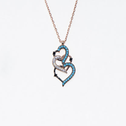 Elegante 925 Silber Halskette mit ineinander verschlungenen rosévergoldeten Herzen. Verziert mit blauen, weissen und schwarzen Zirkonia-Steinen.