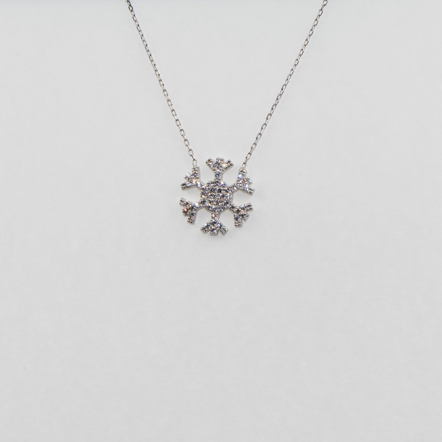 Elegante 925 Silber Halskette mit Schneeflocken Anhänger. Verziert mit funkelnden weissen Zirkonia-Steinen und rhodinierter Oberfläche