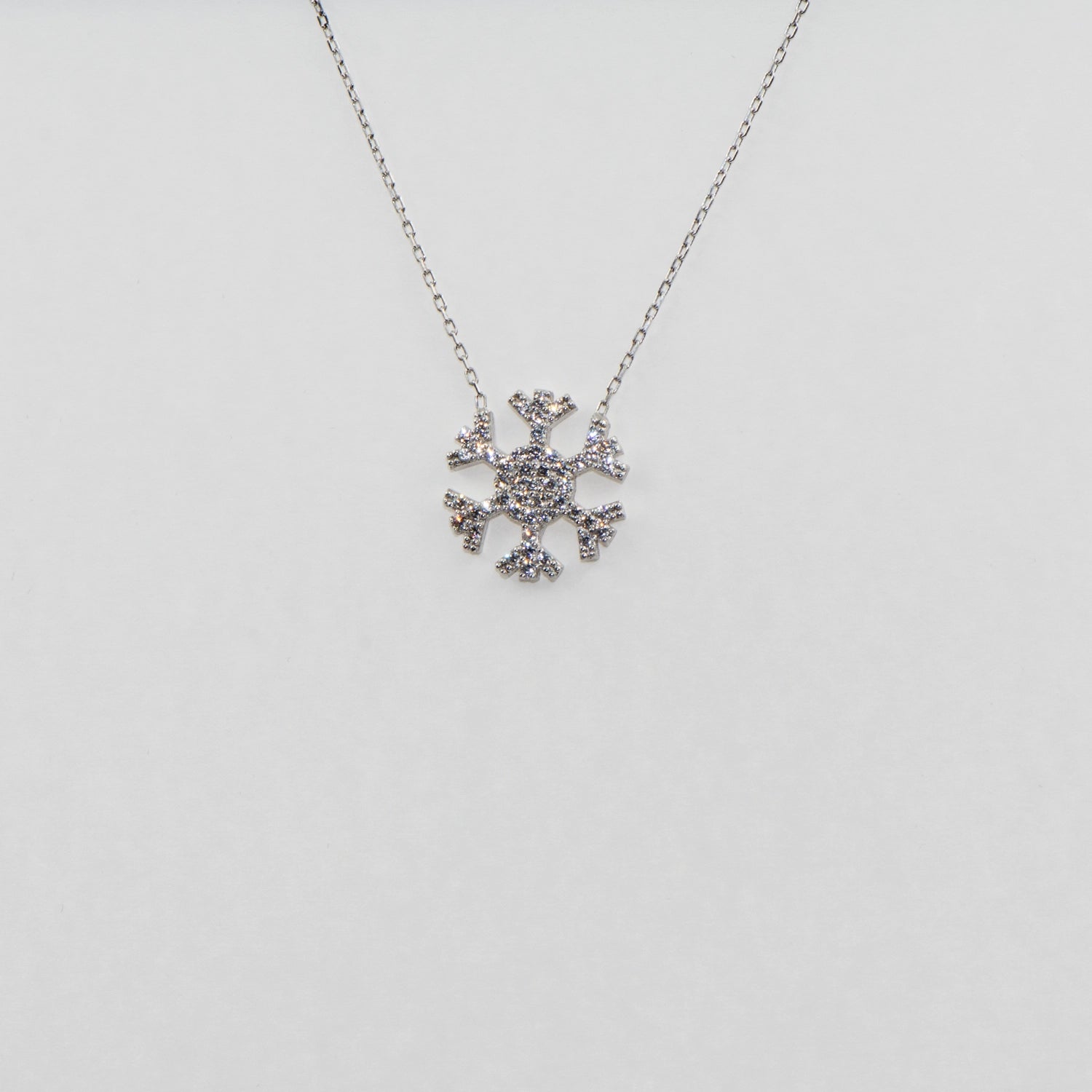 Elegante 925 Silber Halskette mit Schneeflocken Anhänger. Verziert mit funkelnden weissen Zirkonia-Steinen und rhodinierter Oberfläche