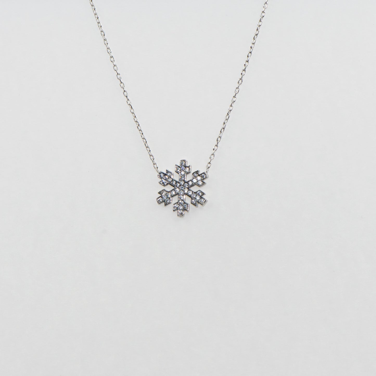 Elegante 925 Silber Halskette mit Stern- und Schneeflocken-Anhänger. Verziert mit funkelnden weissen Zirkonia-Steinen und rhodinierter Oberfläche.