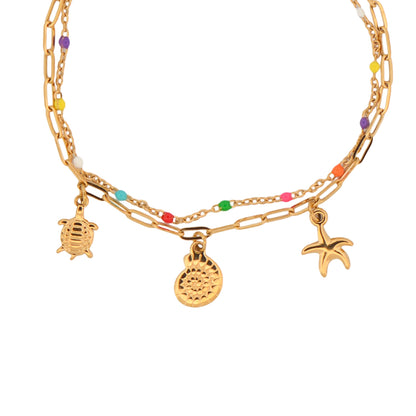 Elegantes Doppelarmband aus Edelstahl in Goldfarbe mit Seestern, Muschel und bunten Perlen. Wasserfest, rostfrei, hautfreundlich und perfekt für Alltag, Ferien und Sommer.