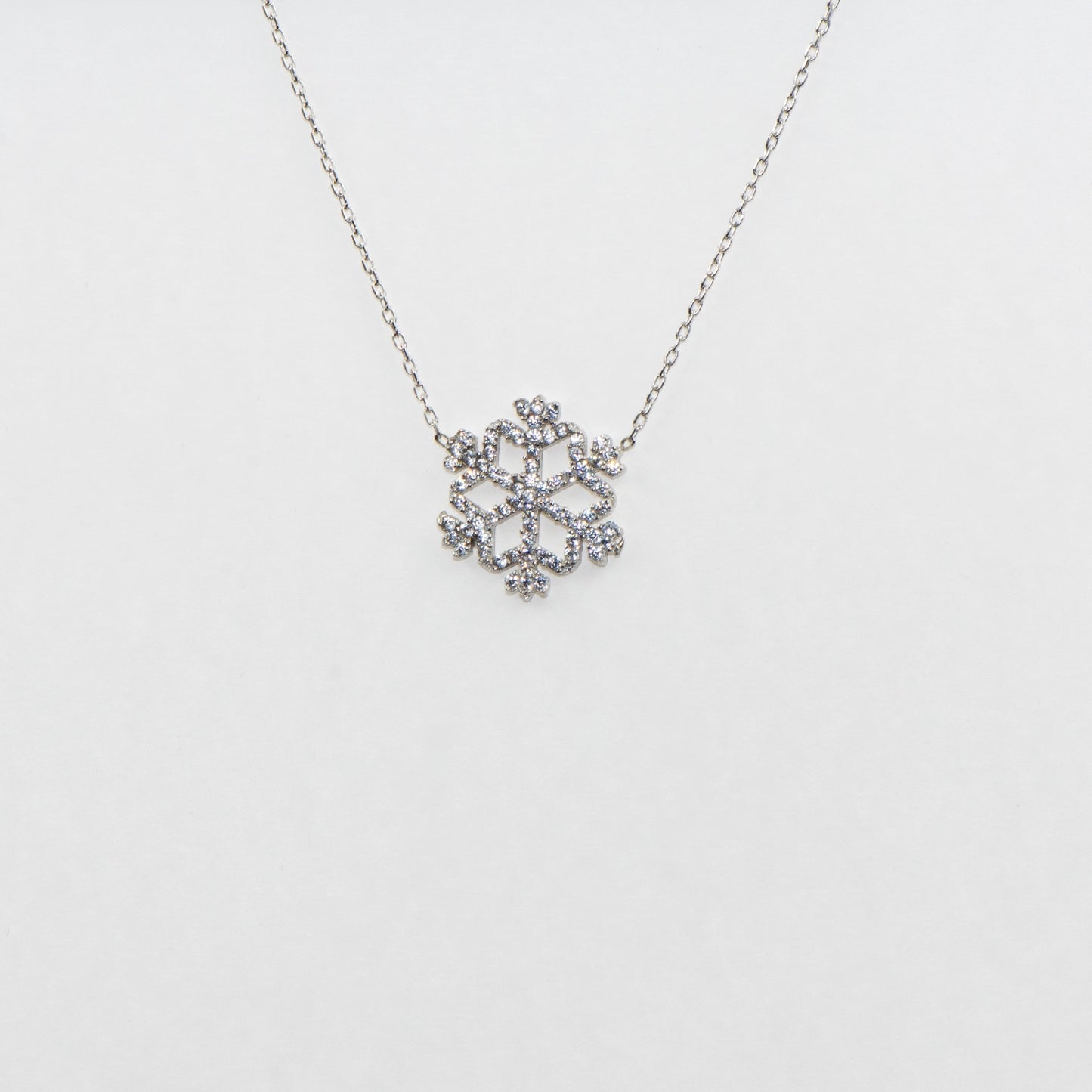 Klassische Schneeflocke Halskette mit Anhänger aus 925 Silber. Verziert mit weissen Zirkonia-Steinen und rhodinierter Oberfläche.