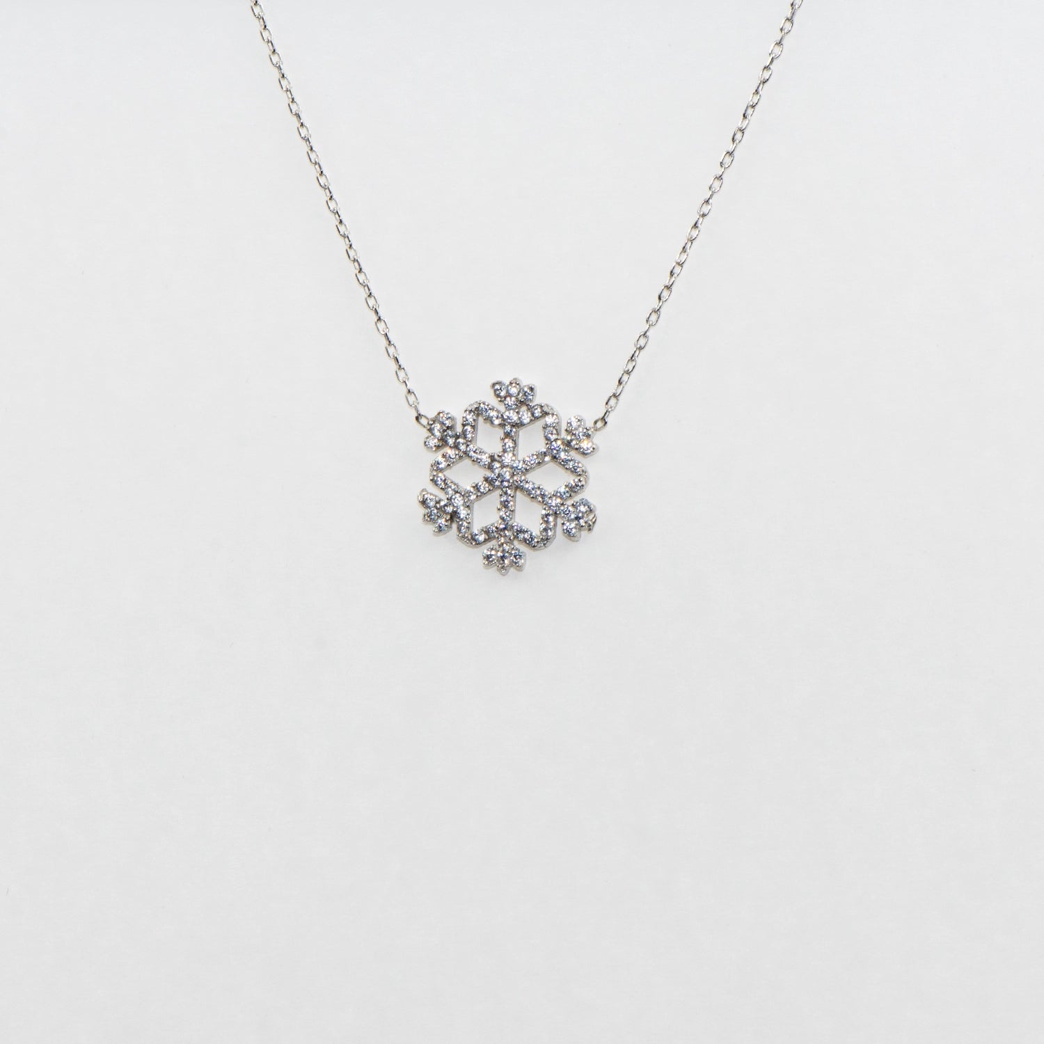Klassische Schneeflocke Halskette mit Anhänger aus 925 Silber. Verziert mit weissen Zirkonia-Steinen und rhodinierter Oberfläche.