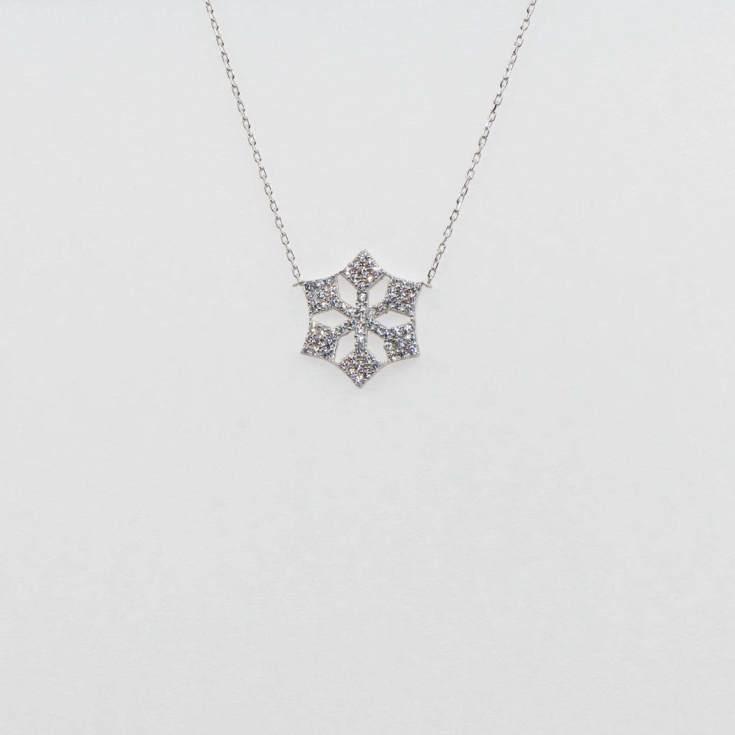 Moderne Schneeflocke Halskette aus 925 Silber mit funkelnden weissen Zirkonia-Steinen und rhodinierter Oberfläche.