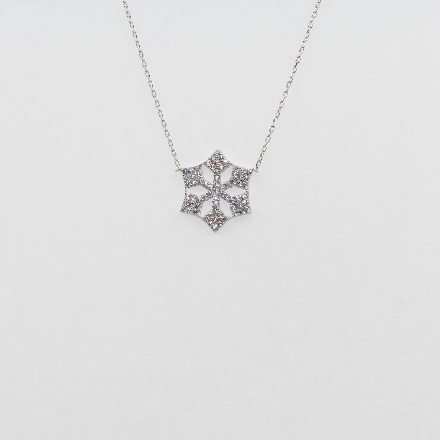 Moderne Schneeflocke Halskette aus 925 Silber mit funkelnden weissen Zirkonia-Steinen und rhodinierter Oberfläche.
