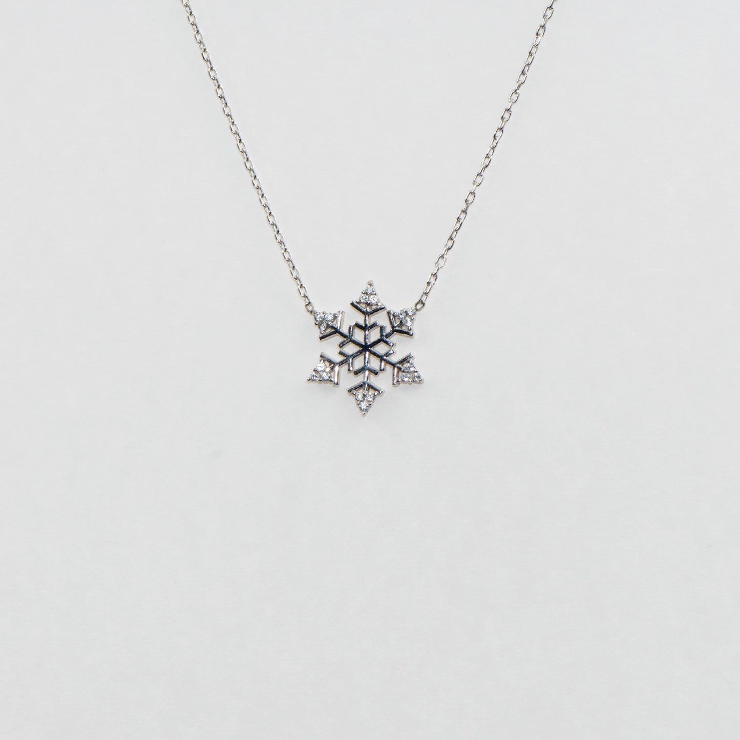 Filigrane Schneeflocke Halskette mit Anhänger CH aus 925 Silber. Verziert mit funkelnden weissen Zirkonia-Steinen und rhodinierter Oberfläche.