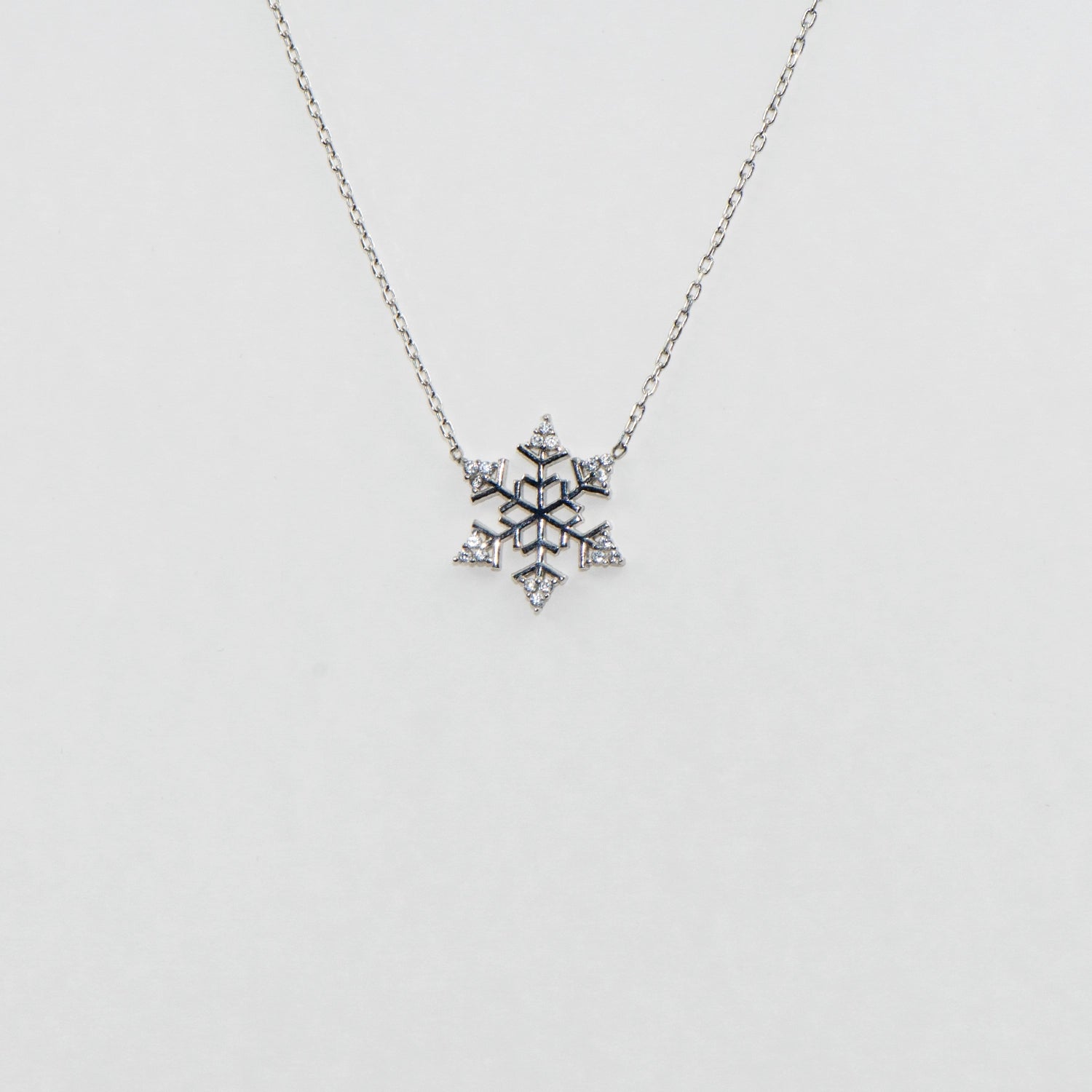 Filigrane Schneeflocke Halskette mit Anhänger CH aus 925 Silber. Verziert mit funkelnden weissen Zirkonia-Steinen und rhodinierter Oberfläche.